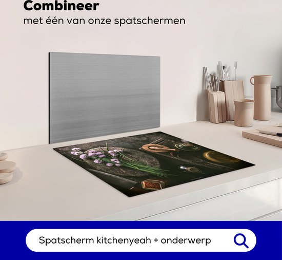 Inductiebeschermer met kruiden en specerijen, naast een spatwand.