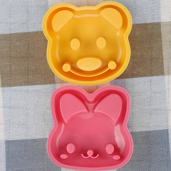Un ours jaune et un emporte-pièce lapin rose sur un tissu à carreaux.