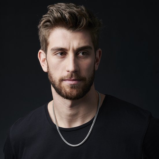 Model met een zilverkleurige schakelketting om zijn nek.