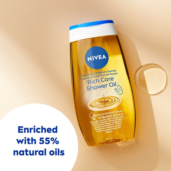 Een gele fles NIVEA Rich Care Shower Oil ligt op een beige ondergrond, met druppels olie ernaast. Tekst op de fles en links.