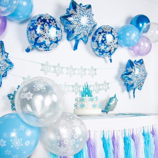 Een gedetailleerd Frozen feestdecoratie opstelling met taart, ballonnen, slingers en een kasteel.