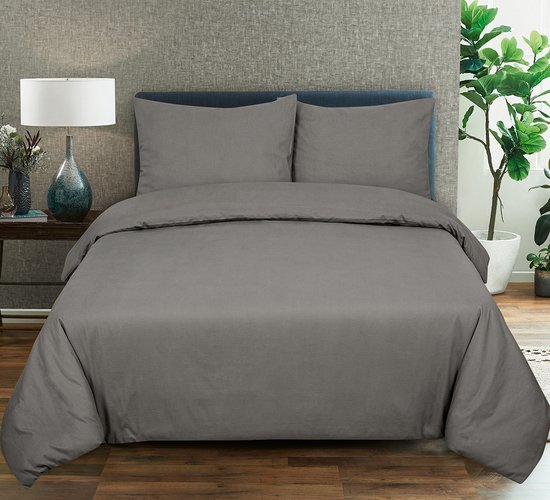 Un lit double avec une housse de couette gris foncé et deux taies d'oreiller, fait dans une chambre.