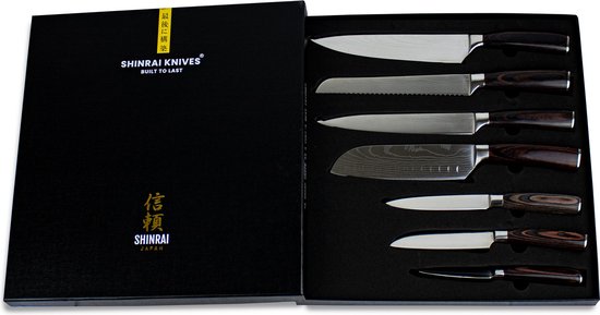 Een open luxe geschenkdoos met zeven Shinrai Japan messen met donkerhouten handvatten.