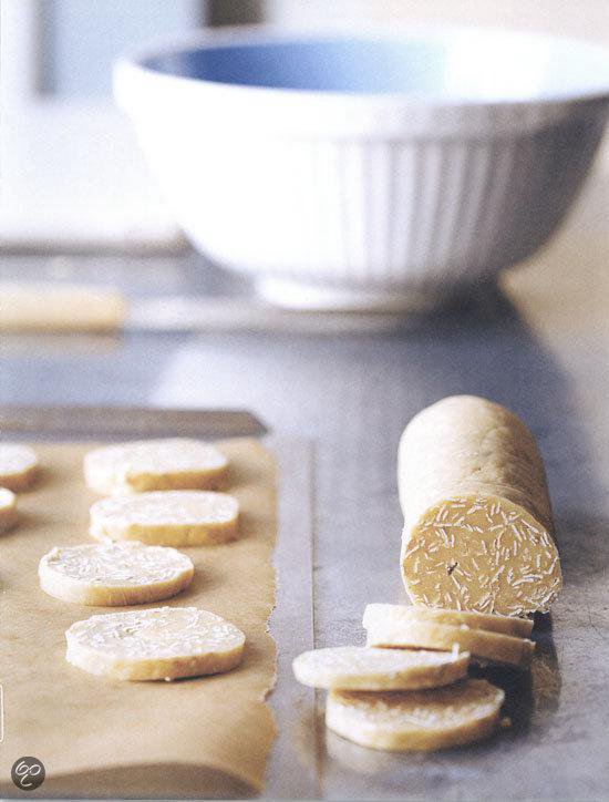 Beslag in een rol op bakpapier, met gesneden plakjes koekjes ernaast.