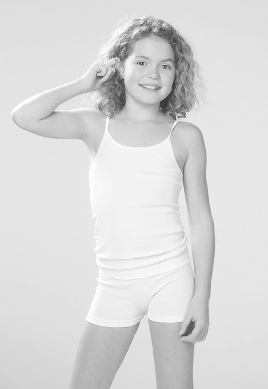 Meisje met krullend haar draagt witte hemd en witte boxer shorts.