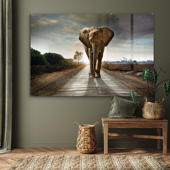 Un éléphant marche sur une route au coucher du soleil, affiché dans un salon.