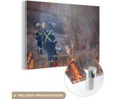 MuchoWow® Glasschilderij 180x120 cm - Schilderij acrylglas - Een brandweer blust een brand die is ontstaan tijdens een hittegolf - Foto op glas - Schilderijen