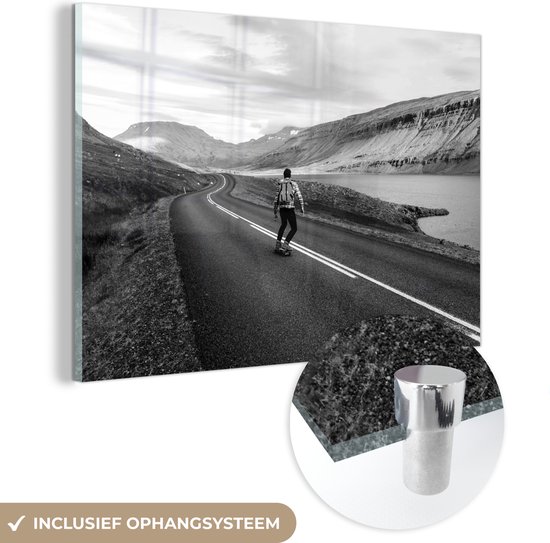 MuchoWow® Glasschilderij 30x20 cm - Schilderij acrylglas - Een man op een skateboard bij een meer in IJsland - zwart wit - Foto op glas - Schilderijen