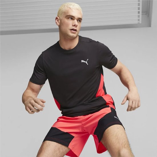 Man in zwart shirt met Puma logo en rode zij-accenten, en een rode shorts.
