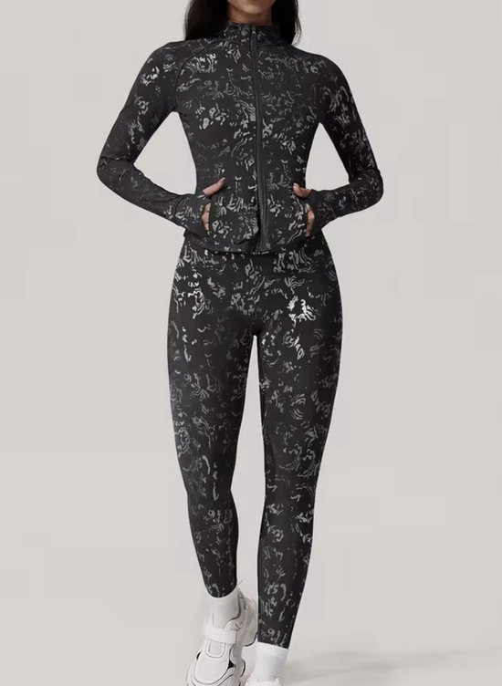 Zwart sportjack met glinsterend patroon, gedragen met bijpassende legging.