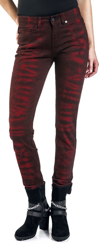 Vrouw in rode skinny jeans met zwarte batikprint, zwart shirt en zwarte laarsjes.