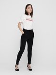 Model draagt zwarte broek met hoge taille en ceintuur, gecombineerd met een wit 'California' T-shirt.