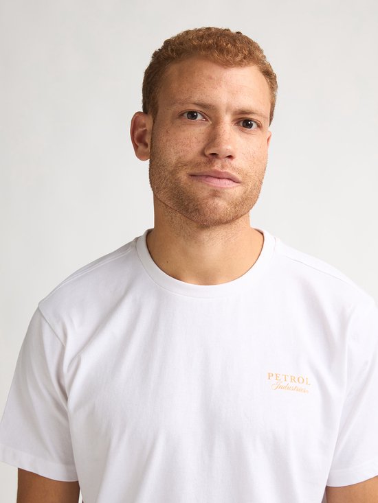 Close-up van man met witte t-shirt met oranje logo op borst.