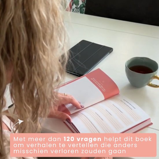 Vrouw met blond haar bladert door een perzikroze invulboek. Op tafel staat een tablet en een kopje thee.