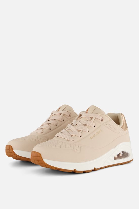 Natuurkleurige Skechers UNO sneakers met witte zolen en goudkleurige accenten.