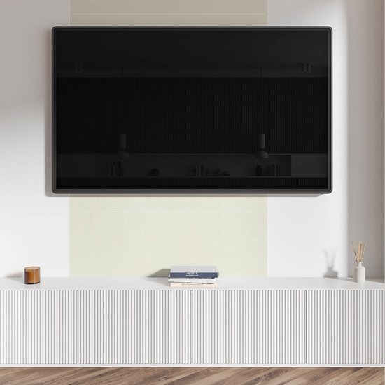 Moderne woonkamer met een grote tv boven een witte kast en lichte, romige tegels op de muur.