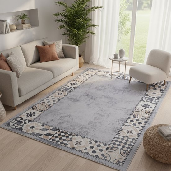 Salon avec un tapis gris à motif de bordure oriental. Le tapis est placé devant un canapé, une chaise et une table d'appoint.