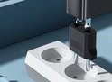 Een zwarte Amerikaanse naar Europese reisstekker adapter met twee pinnen, aangesloten op een wit stopcontact.