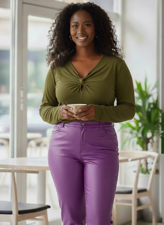 Model draagt een olijfgroene top met gedraaide knoop en paarse leren broek.