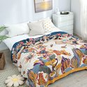 Een sprei met een uitbundig bloemen- en vlinderpatroon in veelkleurige tinten op een crèmekleurige ondergrond.