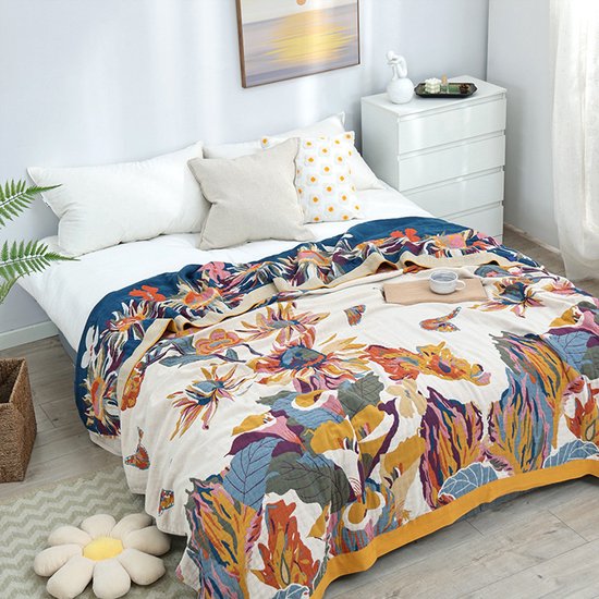 Een sprei met een uitbundig bloemen- en vlinderpatroon in veelkleurige tinten op een crèmekleurige ondergrond.