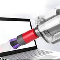 Rood en grijs hulpstuk met paars-zwarte borstelharen, dat een laptop schoonzuigt.