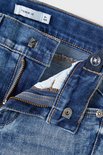 Detail van de gulp van een blauwe spijkerbroek met rits en knopen.