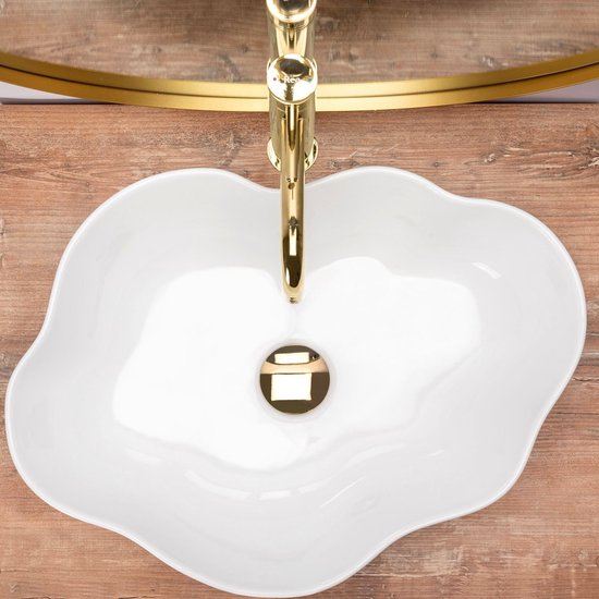 Witte, onregelmatig gevormde waskom met gouden kraan op houten achtergrond.