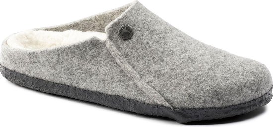 Lichtgrijze vilten Birkenstock pantoffel met schapenvacht voering en zwarte zool, gezien vanuit een hoek.