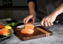 Handen snijden zalm met een 20 cm vleesmes met damascuspatroon.