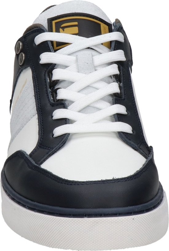 Wit leren sneaker met marineblauwe en grijze accenten, witte veters en een geel logo op de tong.