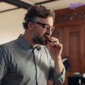 Man met bril eet een Milka Choco Brownie.
