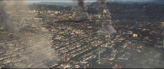 Luchtfoto van een stad met rookpluimen uit gebouwen en twee helikopters.