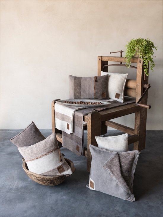 Een houten frame met diverse gebreide kussens in bruin, beige en grijstinten.