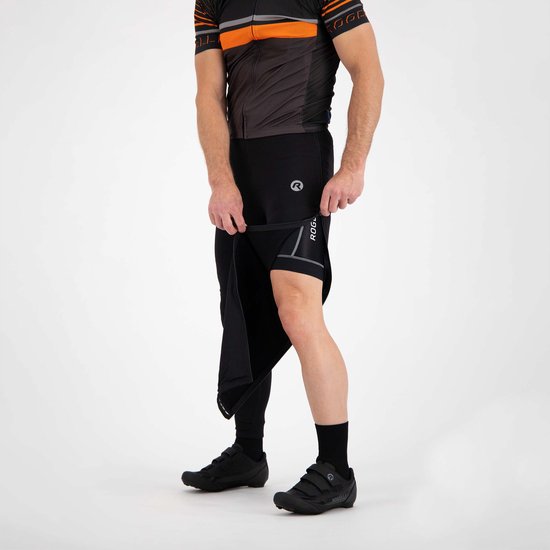 Een man draagt een zwarte fietsbroek met een afneembare pijp en een korte broek met Rogelli-logo, met een grijze rand.