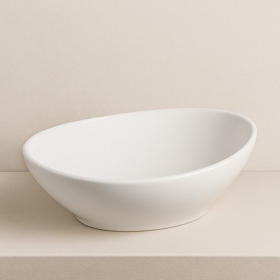 Ovaal witte keramische opbouw waskom geplaatst op een beige ondergrond.