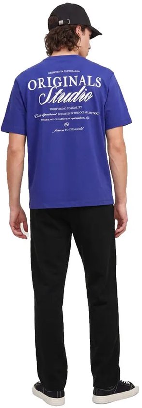 Achteraanzicht van een model in blauw T-shirt met 'ORIGINALS Studio' opdruk en zwarte joggingbroek.