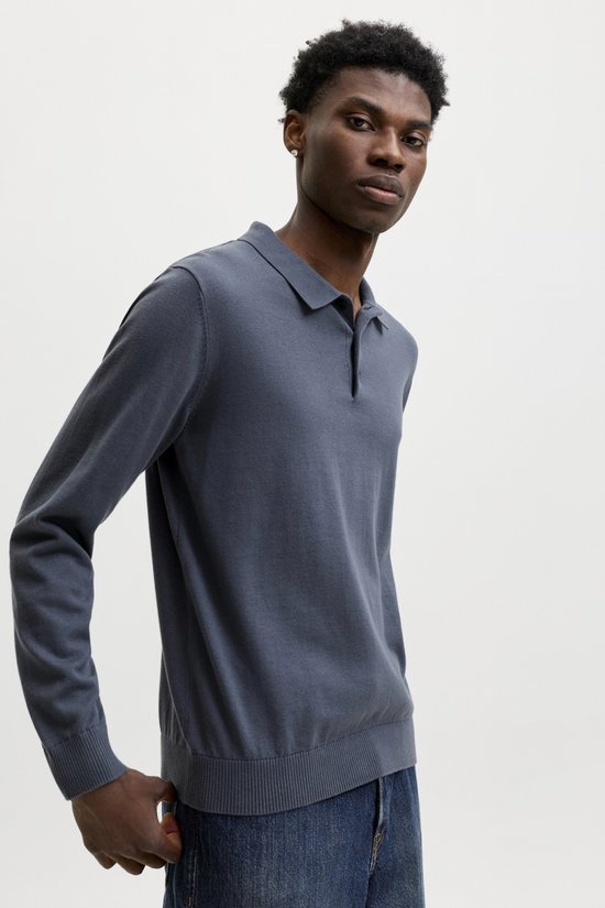 Model draagt een donkerblauwe gebreide lange mouwen polo met jeans.