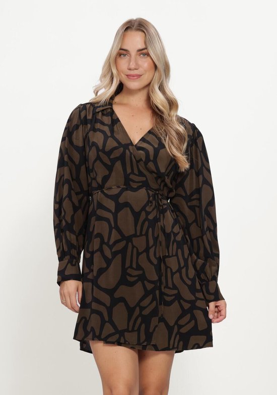 Femme aux cheveux blonds portant une robe portefeuille marron à motif abstrait noir, debout sur fond blanc.