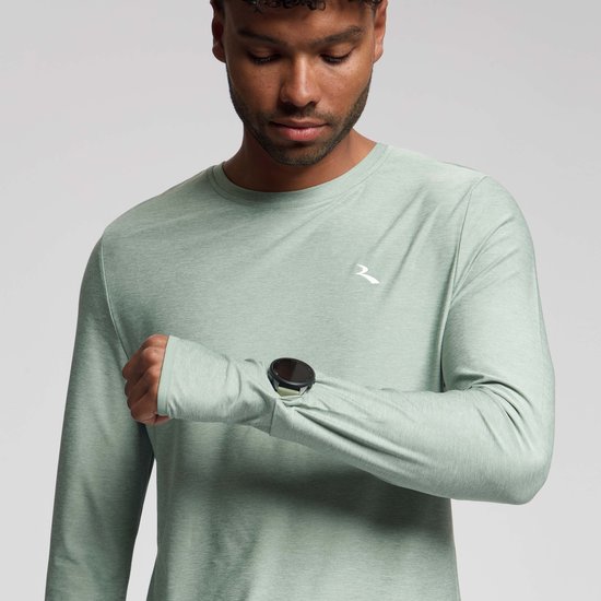 Close-up van een man die naar zijn smartwatch kijkt, draagt een groen Rogelli hardloopshirt met lange mouwen en duimgaten.
