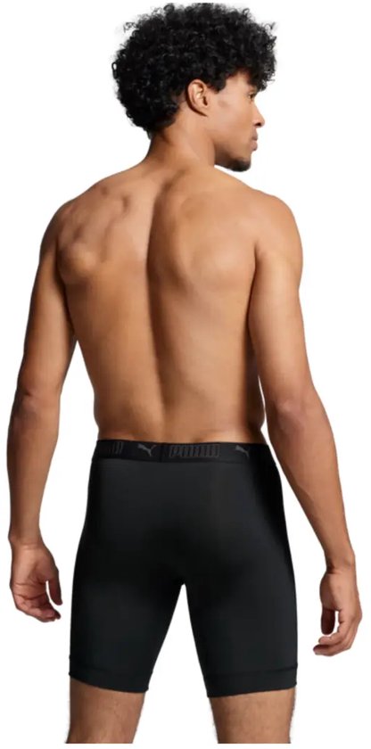 Man met donkere huid, zwart krullend haar, draagt een zwarte PUMA boxershort met lange pijpen.