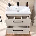 Beige badkamermeubel met witte wastafel, zwarte kraan en twee open lades met zwarte handgrepen.