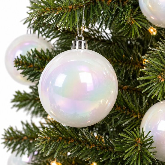Boule de Noël blanche avec un éclat nacré suspendue dans un sapin de Noël vert avec des lumières.