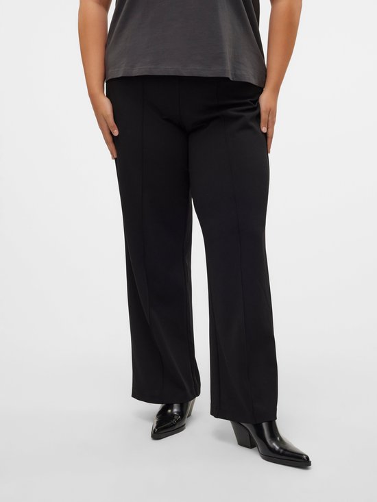 Model draagt een zwarte broek met wijde pijpen en naaddetails aan de voorkant.