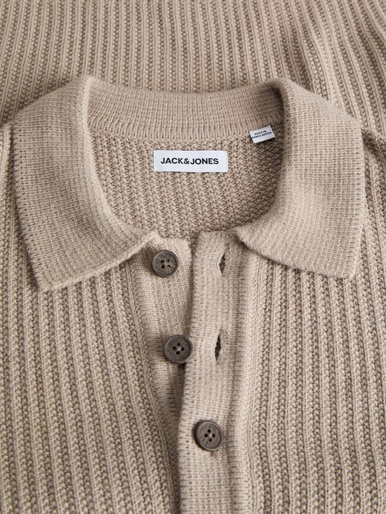 Detailopname van beige gebreide polo met JACK & JONES label en donkere knopen.
