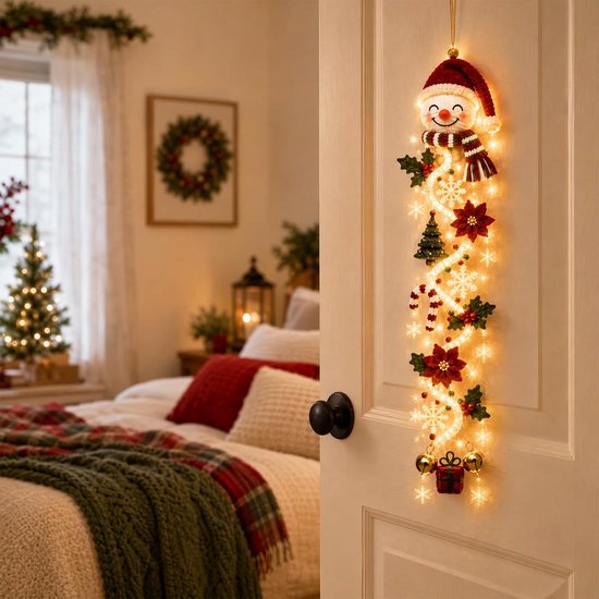 Kerstdeurhanger met sneeuwpop, bloemen en LED-verlichting opgehangen aan een witte deur in een slaapkamer.