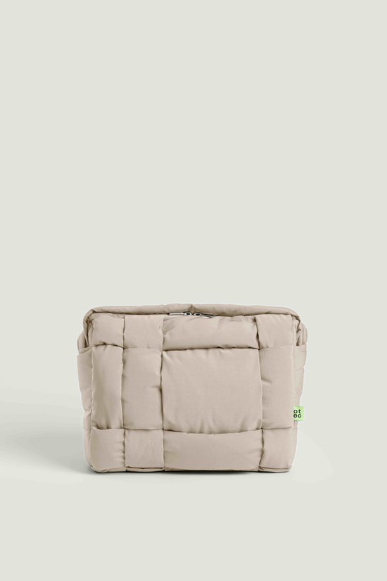 Beige, gewatteerde tas met een vierkant geweven patroon en een klein groen 'otec'-label aan de zijkant.