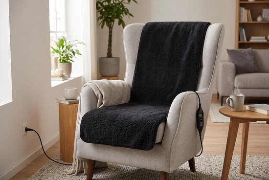 Zwarte, teddy-stijl elektrische stoelverwarmer van 40x120 cm met LCD-controller, liggend op een beige fauteuil.