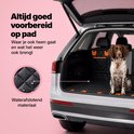 Chien brun et blanc assis sur une couverture pour chien noire avec bordure orange dans le coffre d'une voiture. Insert montre des gouttes d'eau sur le textile.