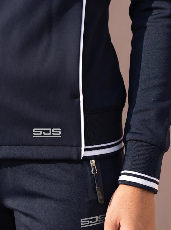 Close-up van de boord en het SJS-logo op een donkerblauwe trainingsbroek en jasje met witte bies.